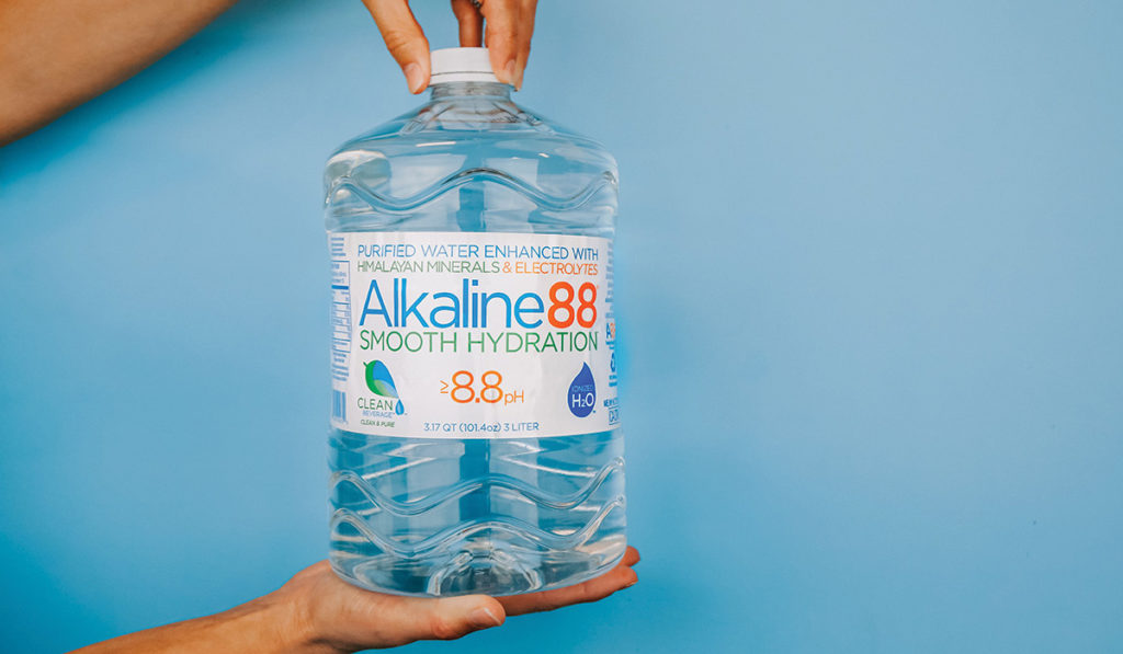 Person opening a large bottle of Alkaline88