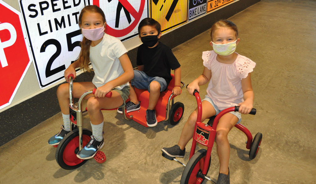 3 children riding trikes inside the Children's Museum